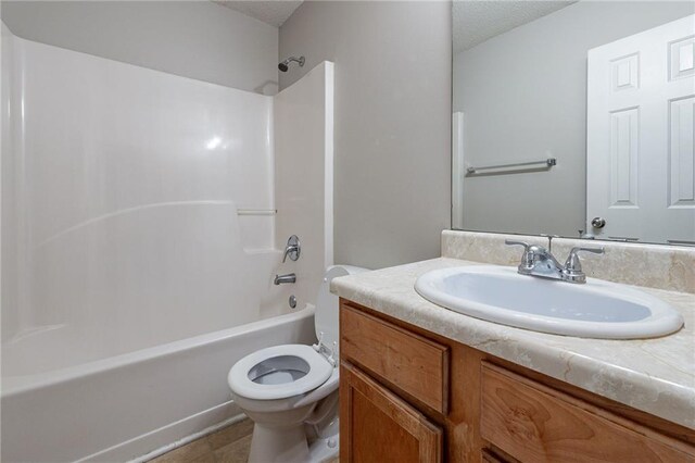 full bathroom featuring vanity, a textured ceiling, toilet, and shower / washtub combination