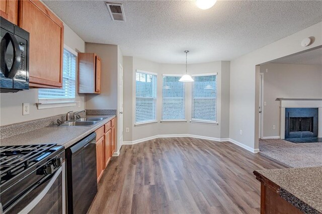 kitchen with black appliances, sink, hanging light fixtures, a textured ceiling, and wood-type flooring