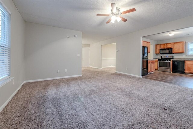 unfurnished living room with ceiling fan, light colored carpet, and a textured ceiling