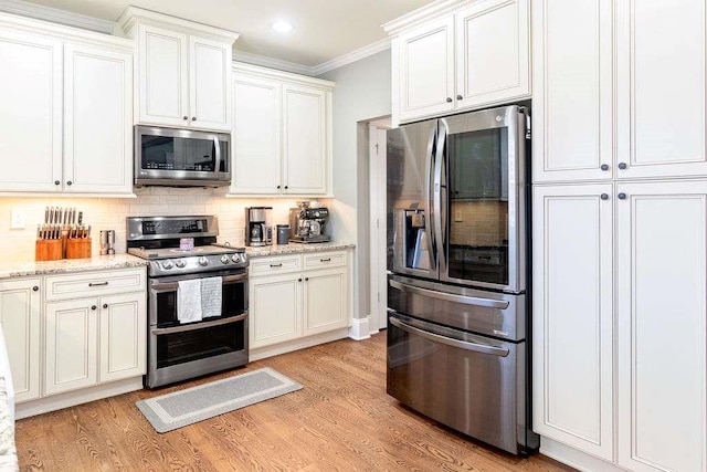 109 Lighthorse Blvd, Mcdonough, GA 30252 - kitchen featuring stainless steel appliances, ornamental molding, decorative backsplash, light wood-style floors, and white cabinets