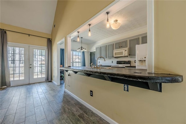 kitchen featuring white appliances, a sink, a kitchen breakfast bar, french doors, and dark wood finished floors