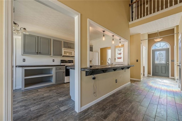 kitchen with dark wood-style flooring, electric range, a kitchen breakfast bar, and white microwave