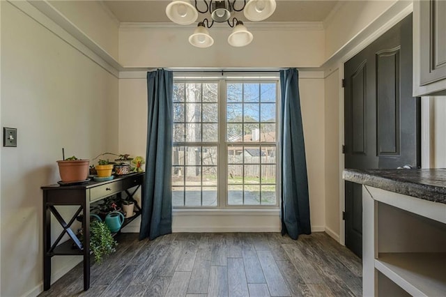 entryway with baseboards, ornamental molding, dark wood-type flooring, and an inviting chandelier