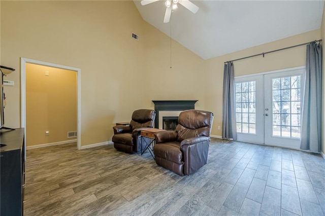 living area featuring french doors, visible vents, a fireplace, and wood finished floors