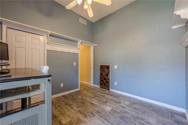 interior space with ceiling fan, wood finished floors, visible vents, and baseboards