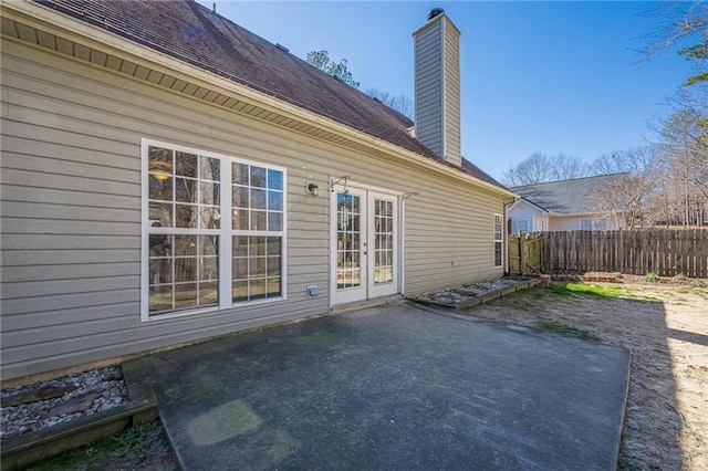 rear view of house featuring french doors, a patio area, fence, and a chimney