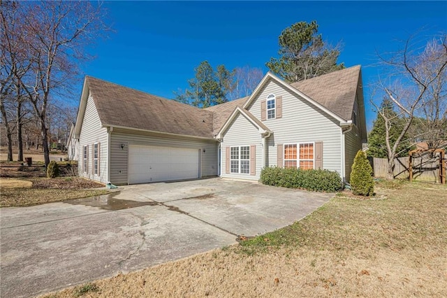 view of front of house with a garage, concrete driveway, roof with shingles, fence, and a front lawn