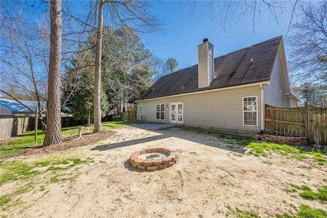 rear view of house with an outdoor fire pit, french doors, a fenced backyard, and a chimney