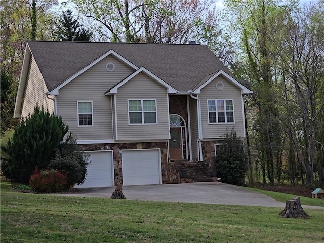 raised ranch featuring stone siding, an attached garage, concrete driveway, roof with shingles, and a front lawn