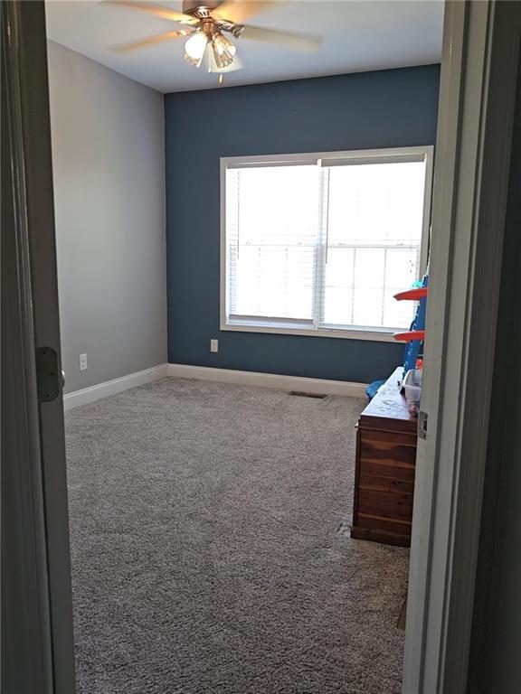 empty room featuring carpet flooring, ceiling fan, and baseboards