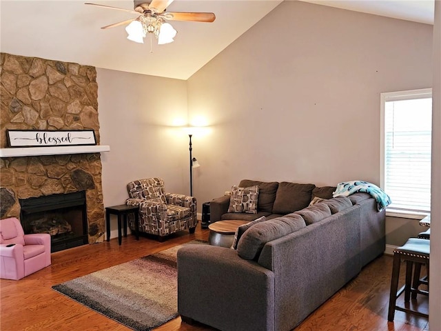 living area with vaulted ceiling, a ceiling fan, wood finished floors, and a fireplace