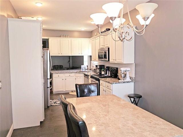 kitchen with appliances with stainless steel finishes, dark wood-style floors, a chandelier, white cabinets, and light stone countertops