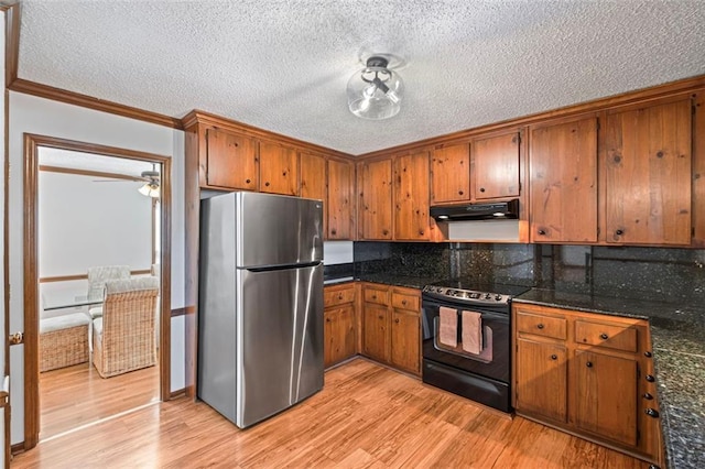 kitchen featuring black electric range, under cabinet range hood, freestanding refrigerator, light wood-style floors, and brown cabinetry