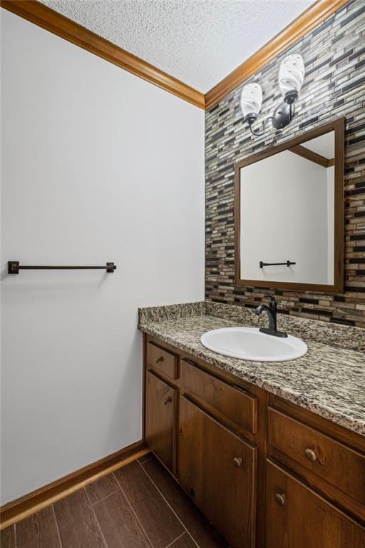 bathroom featuring vanity, baseboards, ornamental molding, a textured ceiling, and backsplash