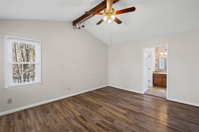 unfurnished bedroom with a ceiling fan, baseboards, ensuite bath, vaulted ceiling with beams, and dark wood-type flooring