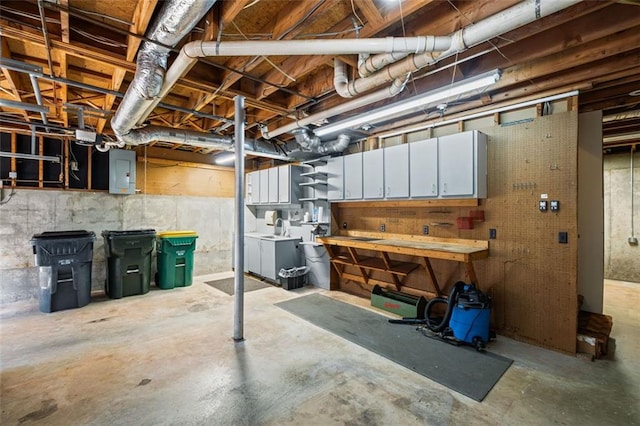 unfinished basement featuring electric panel, a workshop area, and washing machine and clothes dryer