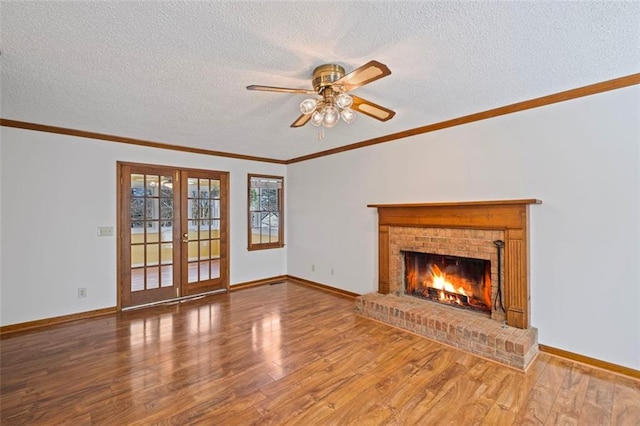 unfurnished living room with ornamental molding, french doors, a fireplace, and wood finished floors