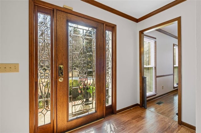 entryway featuring visible vents, baseboards, wood finished floors, and crown molding