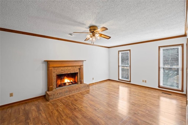 unfurnished living room with a brick fireplace, wood finished floors, and ornamental molding