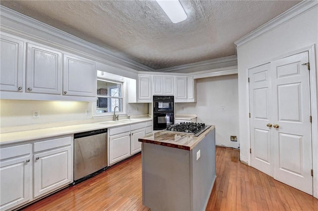 kitchen with appliances with stainless steel finishes, white cabinets, crown molding, wood counters, and light hardwood / wood-style flooring