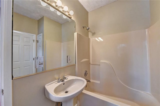 bathroom featuring a textured ceiling, sink, and bathing tub / shower combination