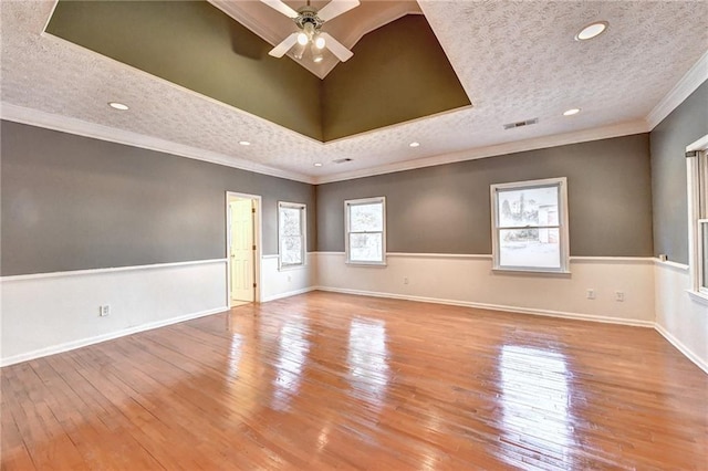 unfurnished room featuring ceiling fan, a textured ceiling, light hardwood / wood-style flooring, ornamental molding, and a tray ceiling