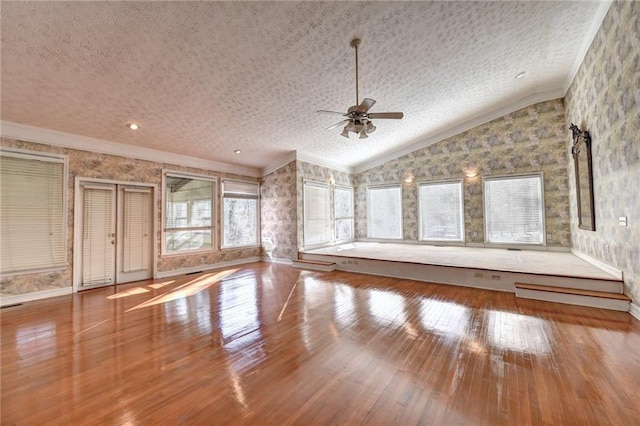 unfurnished living room with ceiling fan, ornamental molding, vaulted ceiling, and wood-type flooring