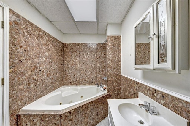 bathroom featuring tile walls, a drop ceiling, tile floors, tiled bath, and vanity with extensive cabinet space