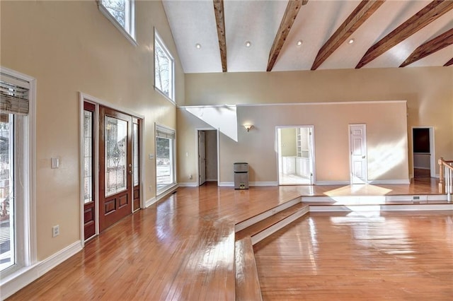 entryway featuring a high ceiling, beam ceiling, and light wood-type flooring