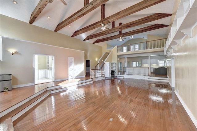 unfurnished living room featuring high vaulted ceiling, beam ceiling, wood-type flooring, and ceiling fan