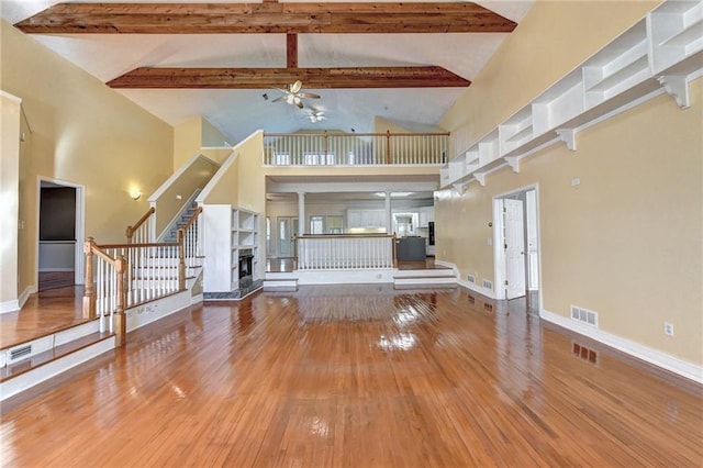 unfurnished living room with high vaulted ceiling, dark wood-type flooring, beam ceiling, and ceiling fan