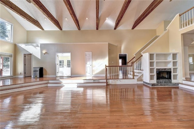 unfurnished living room featuring light hardwood / wood-style floors, high vaulted ceiling, and beamed ceiling