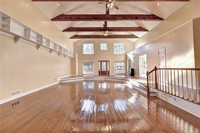 unfurnished living room featuring ceiling fan, high vaulted ceiling, hardwood / wood-style flooring, and beamed ceiling