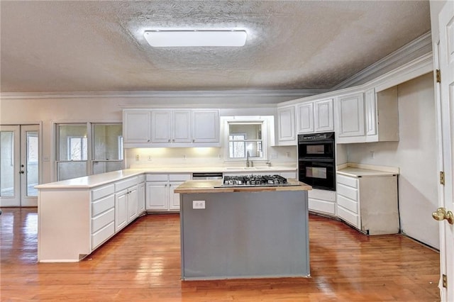 kitchen with white cabinets, light hardwood / wood-style flooring, ornamental molding, and a kitchen island