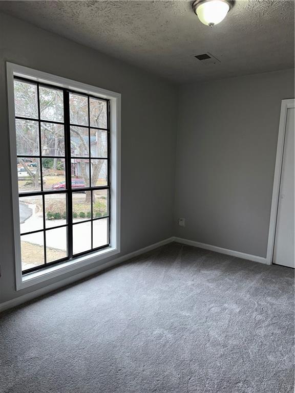 carpeted empty room featuring a textured ceiling