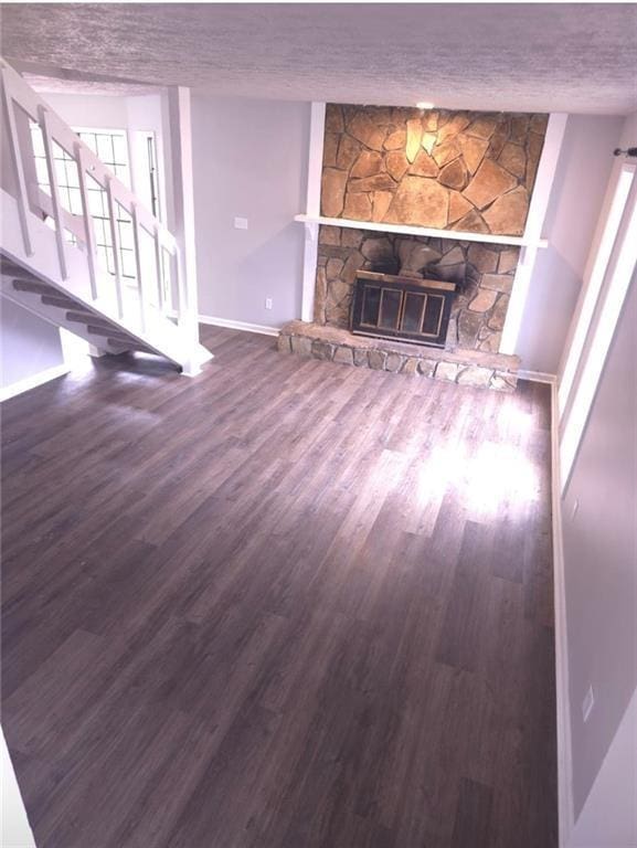 unfurnished living room with plenty of natural light, wood-type flooring, a textured ceiling, and a fireplace