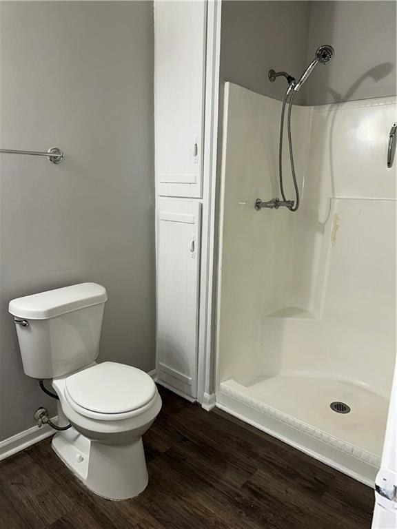 bathroom featuring hardwood / wood-style flooring, a shower, and toilet