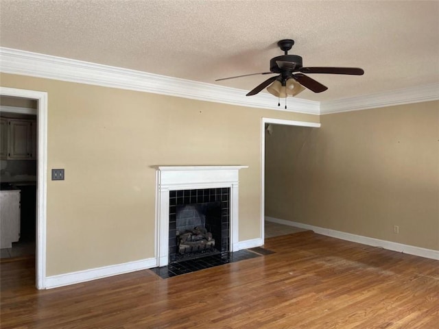 unfurnished living room featuring baseboards, a tile fireplace, wood finished floors, crown molding, and a textured ceiling