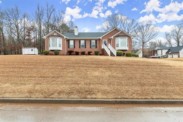 single story home with a front lawn and a storage unit