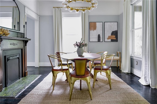 dining area with baseboards, an inviting chandelier, wood finished floors, and a fireplace