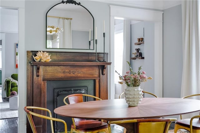 dining area with ornamental molding, a wealth of natural light, and a fireplace
