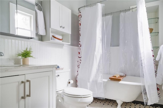 bathroom with toilet, shower / bathtub combination with curtain, vanity, a wainscoted wall, and tile patterned flooring