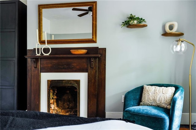 sitting room with a fireplace and a ceiling fan