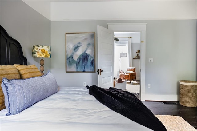 bedroom with baseboards, crown molding, and wood finished floors