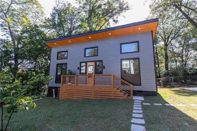 rear view of property with fence, a deck, and a lawn
