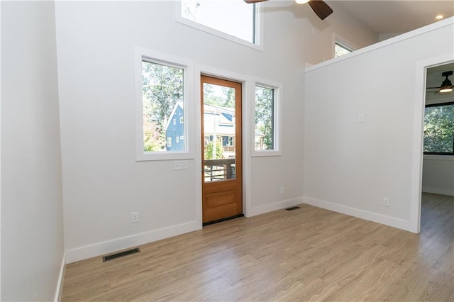 foyer with light wood-style floors, ceiling fan, baseboards, and visible vents