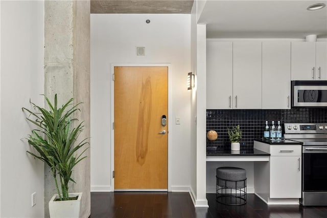 923 Peachtree St NE Unit 1238, Atlanta, GA 30309 - kitchen with stainless steel appliances, dark wood-style floors, white cabinets, backsplash, and dark countertops