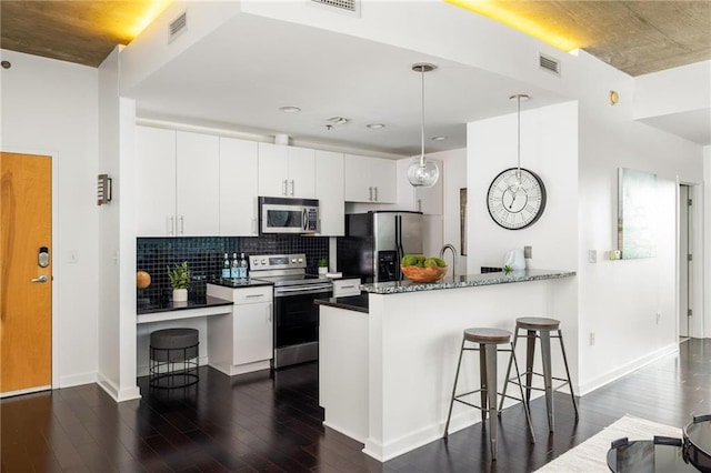923 Peachtree St NE Unit 1238, Atlanta, GA 30309 - kitchen with appliances with stainless steel finishes, dark wood-style flooring, a peninsula, a breakfast bar area, and white cabinets