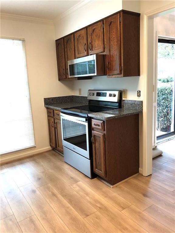 1271 Whitlock Ridge Dr SW, Marietta, GA 30064 - kitchen featuring stainless steel appliances, ornamental molding, light wood-style floors, dark brown cabinetry, and dark stone countertops