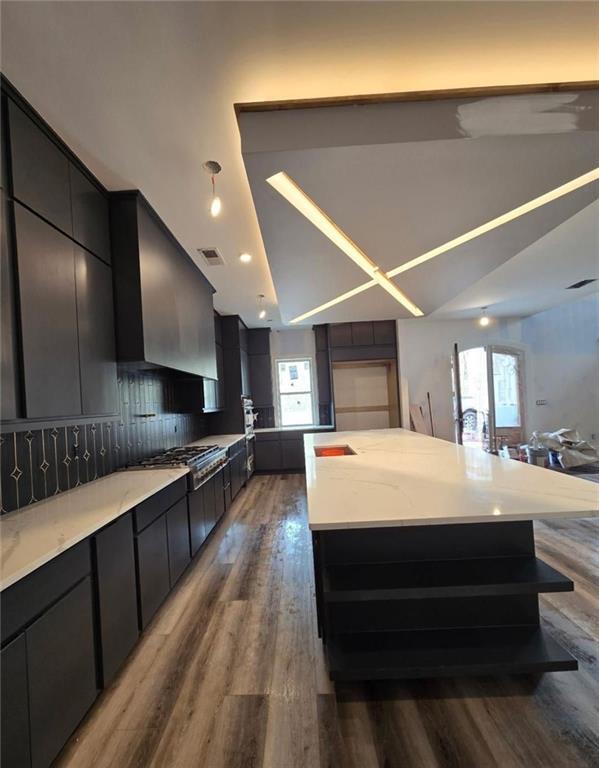 300 Mountain Ridge Dr, Dahlonega, GA 30533 - kitchen with gas stovetop, wall chimney range hood, visible vents, wood finished floors, and lofted ceiling